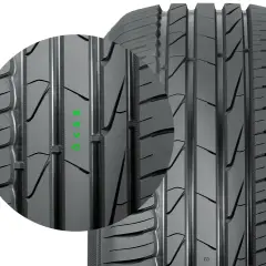 Zbliżenie na bieżnik opony Nokian, firmy znanej z produkcji opon zimowych. Widoczne zielone oznaczenia.