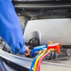 Mechanik sprawdza, ile czynnika do klimatyzacji jest w samochodzie, używając manometrów.