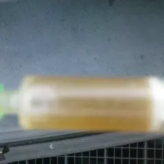 Strzykawka z żółtym płynem chłodniczym na tle deski rozdzielczej.