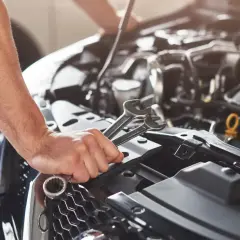 Mechanik z kluczami w dłoni pracuje przy silniku. Kod p0089 może oznaczać problem z układem paliwowym.