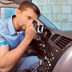 Mężczyzna w samochodzie czuje nieprzyjemny zapach z nawiewów. Czy to problem z klimatyzacją w samochodzie?