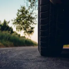 Opona na feldze 8j gotowa na podróż. Zbliżenie na bieżnik i drogę w tle.