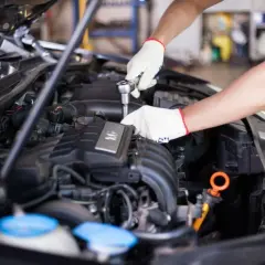 Mechanik w białych rękawiczkach naprawia silnik, być może rozwiązując problem dtc p0120 renault.