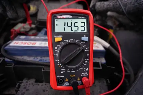 Multimetr pokazuje 14.53V, co jest kluczowe, jak sprawdzić alternator. Pomiar napięcia na akumulatorze.