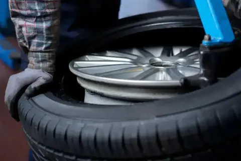 Mechanik w warsztacie wymienia oponę na feldze. Zastanawiasz się, ile kosztuje wymiana opon?