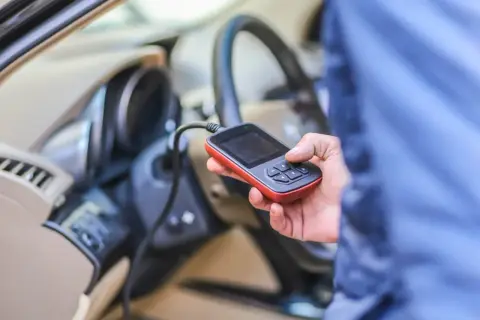 Diagnostyka Renault: ręka trzyma czytnik OBD, który może wykryć błąd DTC B1267.