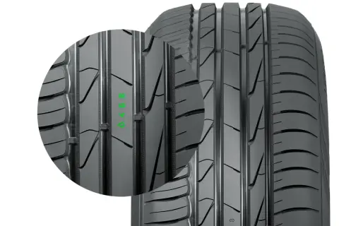 Zbliżenie na bieżnik opony Nokian, firmy znanej z produkcji opon zimowych. Widoczne zielone oznaczenia.