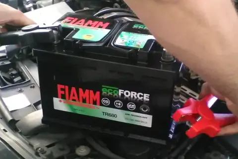 Ręce podłączają kable do akumulatora FIAMM ecoFORCE. Widoczne oznaczenia na akumulatorze, w tym model TR680 i technologia AFB.