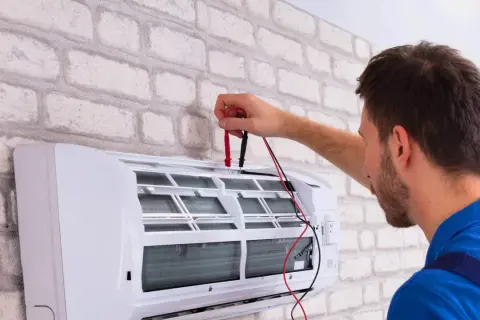 Technik sprawdza działanie klimatyzacji, przygotowując ją do dezynfekcji.