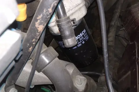 Filtr oleju BOSCH p0011 w silniku, otoczony przewodami i elementami mechanicznymi.