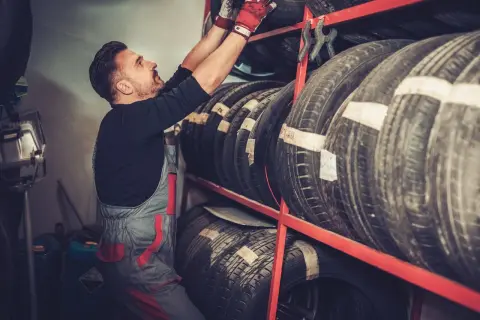 Mechanik w czerwonych rękawiczkach układa opony. Czy to Laufenn? Co to za firma?