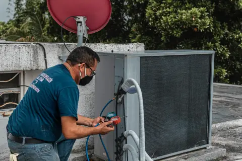 Technik sprawdza czujnik ciśnienia klimatyzacji za pomocą manometru.