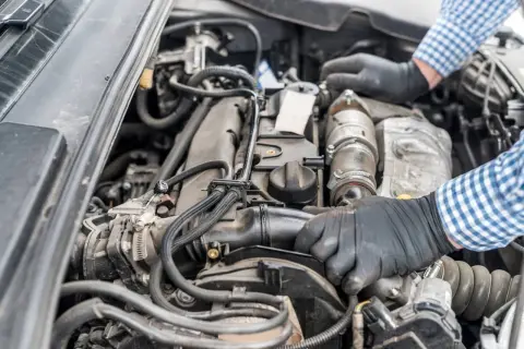 Mechanik w rękawiczkach naprawia silnik Renault, być może z powodu błędu dtc p0141.