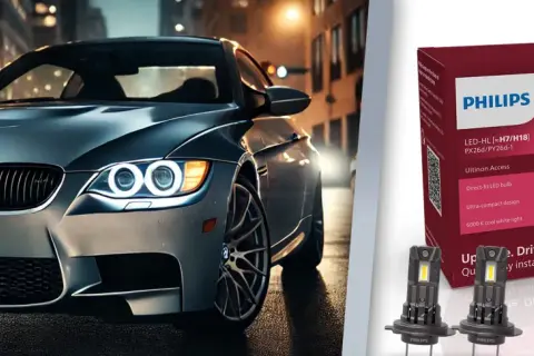 Srebrne auto z włączonymi światłami LED na tle miasta. Obok opakowanie żarówek Philips Ultinon Access, które jakie żarówki odmienią nocną jazdę.