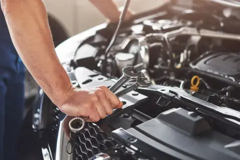 Mechanik z kluczami w dłoni pracuje przy silniku. Kod p0089 może oznaczać problem z układem paliwowym.