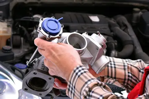 Mechanik trzyma turbosprężarkę, pokazując jej budowę. Czujnik ciśnienia doładowania jest integralną częścią tego elementu.