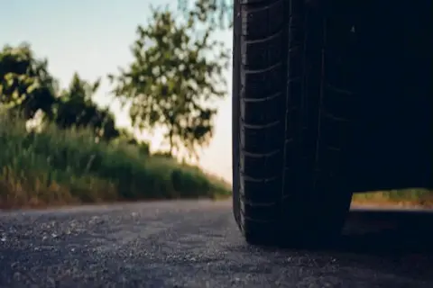 Opona na feldze 8j gotowa na podróż. Zbliżenie na bieżnik i drogę w tle.