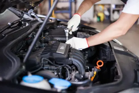 Mechanik w białych rękawiczkach naprawia silnik, być może rozwiązując problem dtc p0120 renault.