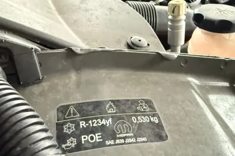 Naklejka z informacją o czynniku klimatyzacji R-1234yf i jego cenie. Wskazuje na ilość 0,530 kg.