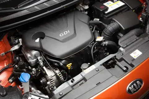 Silnik GDi 1.4 mpi w samochodzie Kia. Widoczny jest blok silnika, akumulator i elementy układu dolotowego.