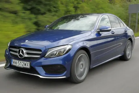 Niebieski Mercedes-Benz c205 w ruchu, z rozmytym tłem zieleni i drogi.