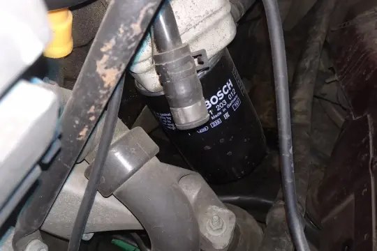 Filtr oleju BOSCH p0011 w silniku, otoczony przewodami i elementami mechanicznymi.