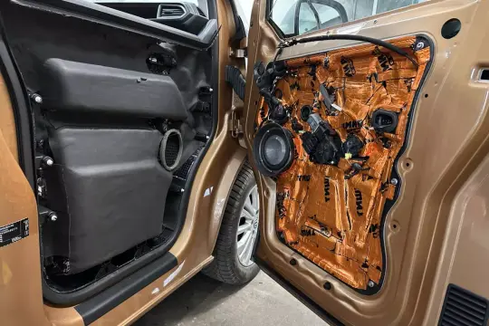 Wnętrze drzwi samochodu po demontażu tapicerki. Widoczna instalacja audio i materiały wygłuszające. SDVC co to? To system aktywnej kontroli głośności.