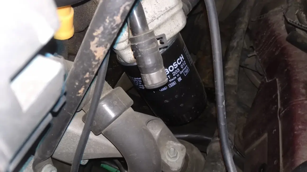 Filtr oleju BOSCH p0011 w silniku, otoczony przewodami i elementami mechanicznymi.
