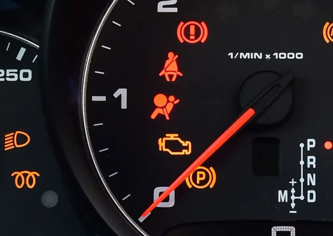Kontrolka SRS airbag świeci się, sygnalizując problem z poduszkami powietrznymi. Obok widać kontrolki hamulca, pasów, silnika i skrzyni biegów.
