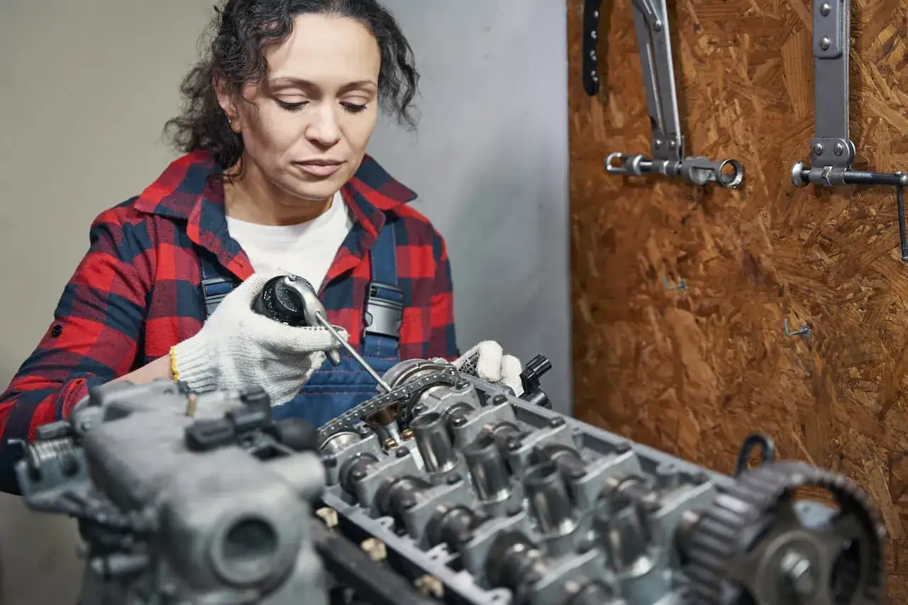 Mechaniczka z precyzją smaruje łańcuch rozrządu, mając nadzieję, że zatarty silnik odpali.