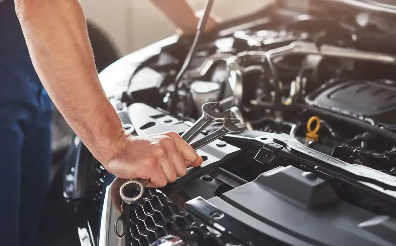 Mechanik z kluczami w dłoni pracuje przy silniku. P008700.