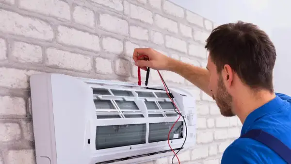 Technik sprawdza działanie klimatyzacji, przygotowując ją do dezynfekcji.