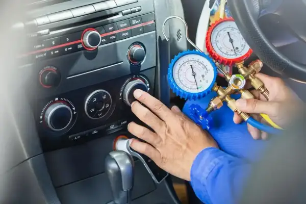 Mechanik sprawdza ciśnienie czynnika klimatyzacji R1234yf za pomocą manometrów.