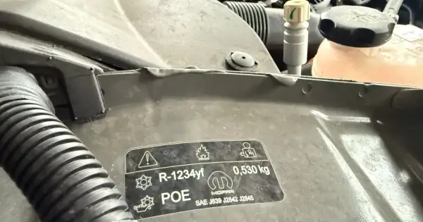 Naklejka z informacją o czynniku klimatyzacji R-1234yf i jego cenie. Wskazuje na ilość 0,530 kg.